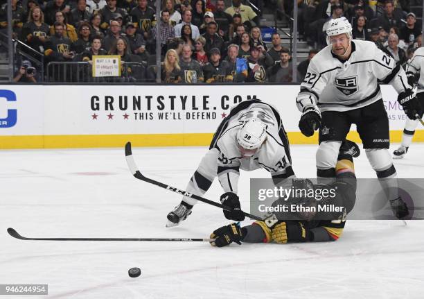 William Carrier of the Vegas Golden Knights tries to stay with the puck as he gets knocked down by Paul LaDue and Trevor Lewis of the Los Angeles...