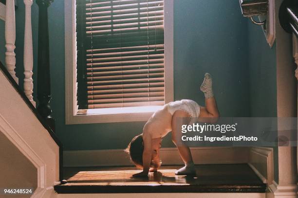 two years old toddler wearing diapers doing yoga on the stairs at home - 2 3 years stock pictures, royalty-free photos & images