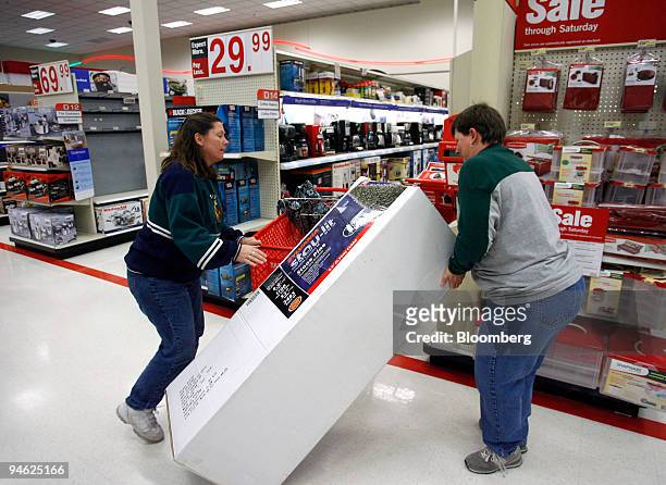 Lori Hanson, left, and Kim Hartman handle an artificial Christmas tree, that has been reduced in price, at a Target store in Mission, Kansas, U.S.,...