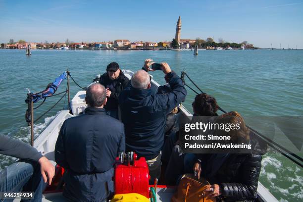 Tourists sail a canal on a boat of a fishing tour organized by Cooperativa San Marco in Burano on April 14, 2018 in Venice, Italy. At the beginning...