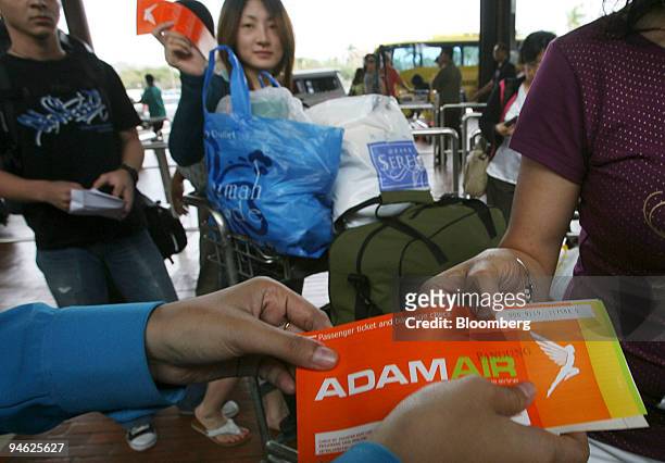 An airport employee inspects the tickets of Adam Air passengers prior to boarding at Soekarno-Hatta International Airport in Cengkareng, Jakarta,...