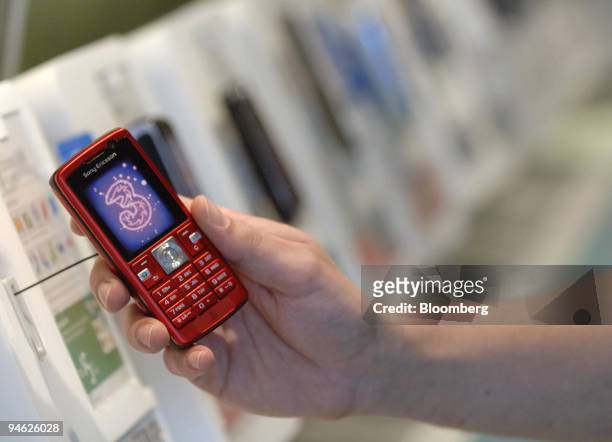 Shopper holds up a "3G" mobile phone, which is owned by Hutchison Telecommunications International Ltd., in Sydney, Australia, Feb. 26, 2007....