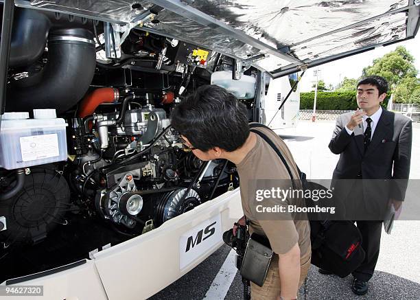 Journalists examine the engine room of Mitsubishi Fuso Truck & Bus Corp.'s Aero Queen Super Hi Decker Bus in Tokyo, Japan, on Friday, June 15, 2007....