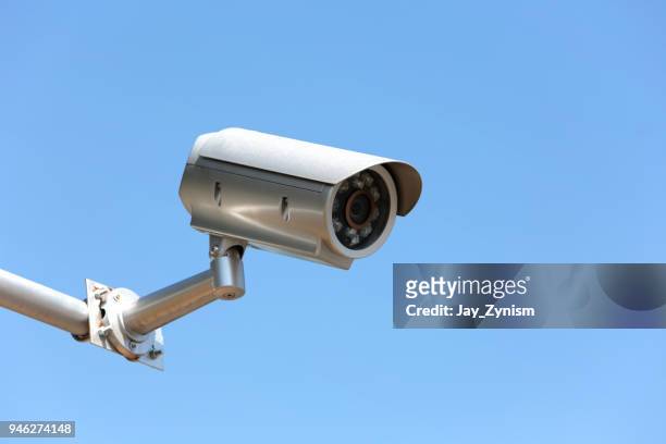 low angle view of security camera against clear blue sky - security camera stock pictures, royalty-free photos & images