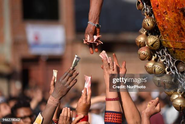 Nepalese devotees offering money to priest in chariot during the pull down 'Linga' a wodden pole during the celebration of Bisket Jatra Festival at...