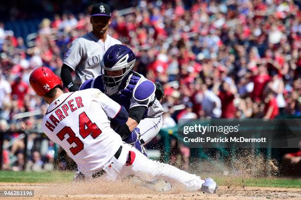 Bryce Harper of the Washington Nationals slides in safely to score ahead of the tag by catcher Tony Wolters of the Colorado Rockies in the sixth...