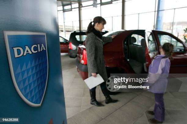 Woman and her daughter look at a Dacia Logan at a dealership in Bucharest, Romania, on Friday, Feb. 23, 2007. With the Logan, Renault set out to...