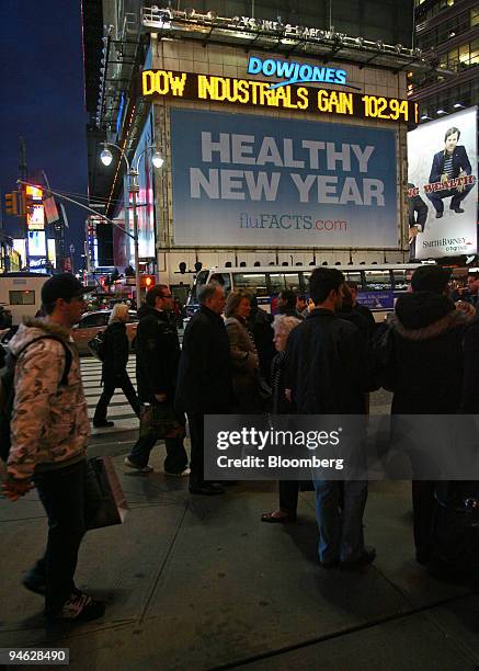 Pedestrians pass the Dow Jones ticker and other signage in Times Square, Wednesday, December 27 in New York. U.S. Stocks rose for a second day as...