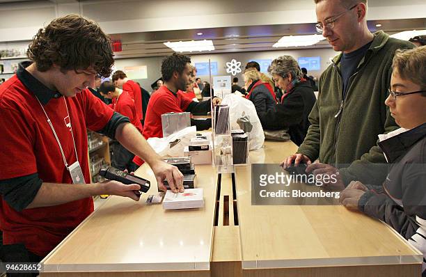 Apple Store employee Neal Ellis, left, scans an item for customer Chancy Arnold and his son Chancy Jr., in the Apple Store on Fifth Avenue in New...