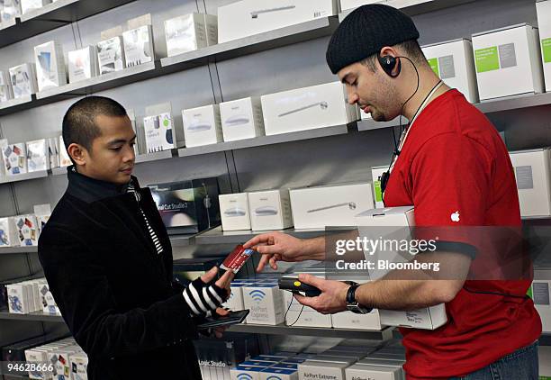 Apple Store employee Alex Alvarez, right, takes the credit card of customer Nic Aldana as he checks-out using a handheld device in the Apple Store on...