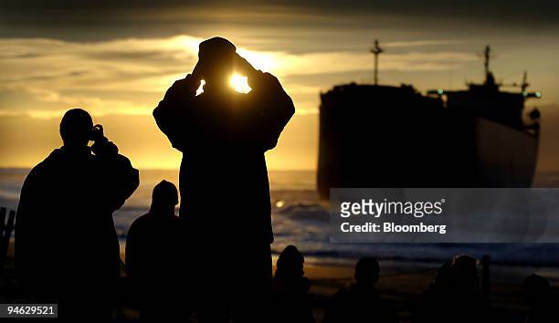 Locals take photographs at dawn of the coal vessel Pasha Bulker, which ran aground last week, at Nobbys Beach, south of the entrance to Newcastle...