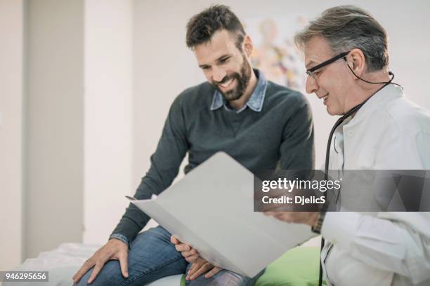doctor masculino madura feliz leyendo el resultado de la gran prueba a su paciente agradecido. - male doctor man patient fotografías e imágenes de stock