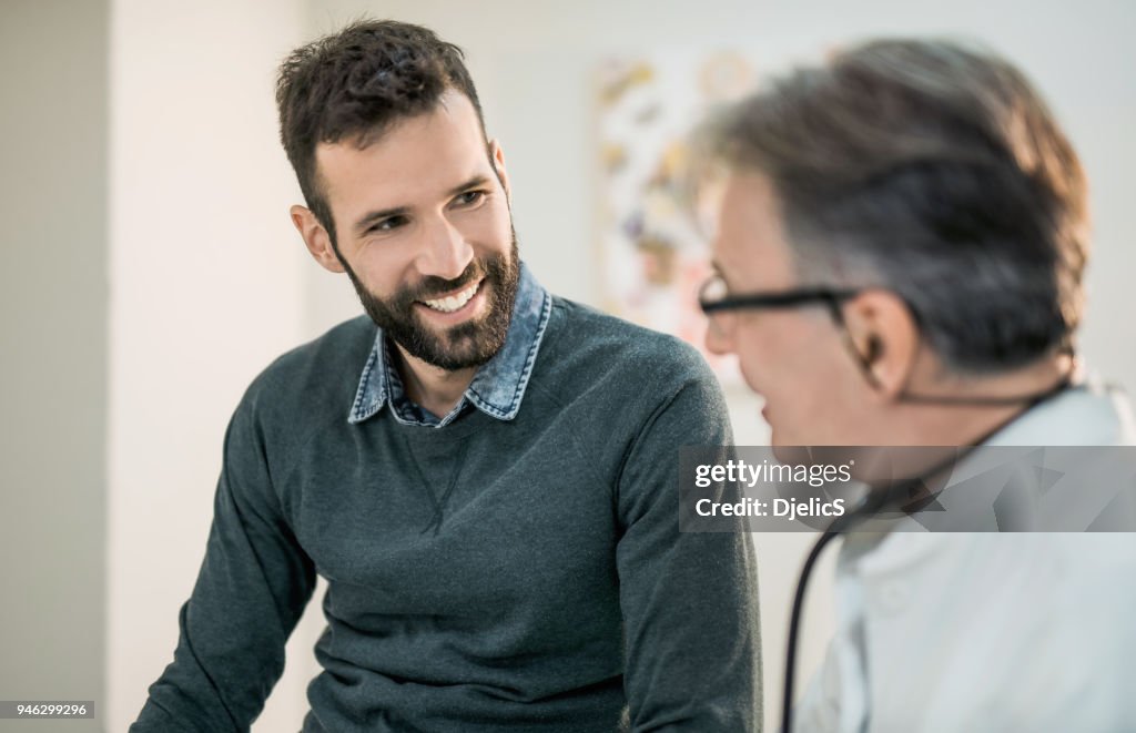 Glücklich Mitte erwachsenen männlichen Patienten im Gespräch mit seinem Arzt.