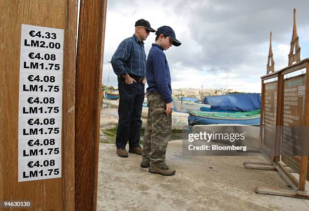 Tourists look at menu prices which are displayed in lira and euro at a restaurant in Marsaxlokk, Malta, on Wednesday, Dec. 19, 2007. The Maltese...