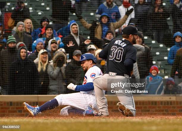 Kyle Schwarber of the Chicago Cubs scores on a wild pitch as Peter Moylan of the Atlanta Braves covers home plate during the eighth inning on April...