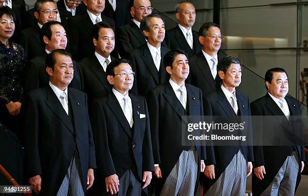 Shinzo Abe, prime minister of Japan, foreground center, poses with his newly appointed cabinet members during a photo session after their first...