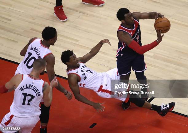 DeMar DeRozan and Jonas Valanciunas watch as Toronto Raptors guard Kyle Lowry takes the charge from Washington Wizards guard John Wall as the Toronto...