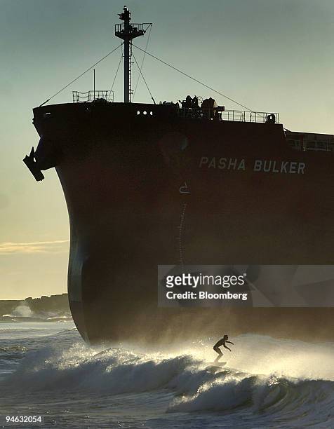 Lone surfer braves the early morning waves near the beached container ship, the 'Pasha Bulker', on Nobby's beach at the entrance to Newcastle Port,...