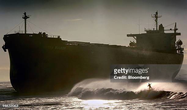 Lone surfer braves the early morning waves near the beached container ship, the 'Pasha Bulker', on Nobby's beach at the entrance to Newcastle Port,...