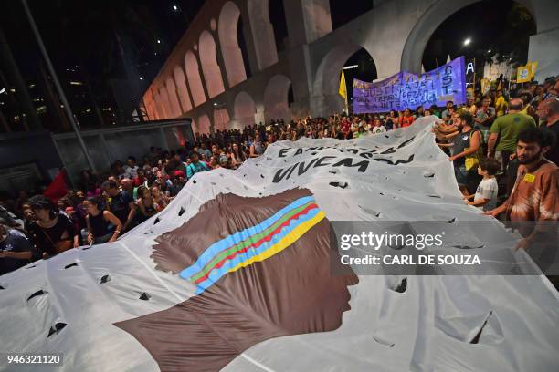 Giant banner depicting Marielle Franco's profile, is displayed during a demonstration marking one month of her murder in Lapa, Rio de Janeiro, Brazil...