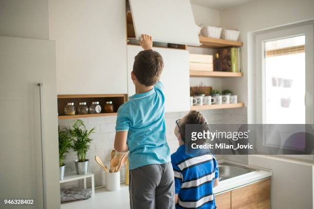brothers stealing cookies in kitchen - kitchen bench top stock pictures, royalty-free photos & images