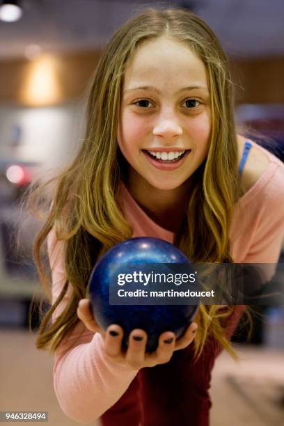 portrait of cute long hair preteen girl playing bowling. - bowling alley stock pictures, royalty-free photos & images