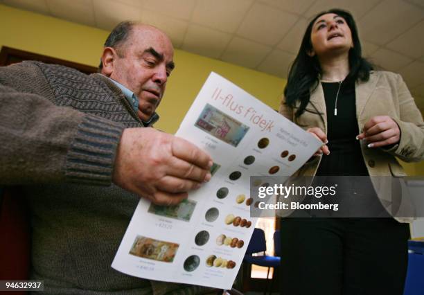 Walter Muscat, of Attard, Malta, left, looks over study materials about the euro as Carine Callus, an information officer from the National Euro...