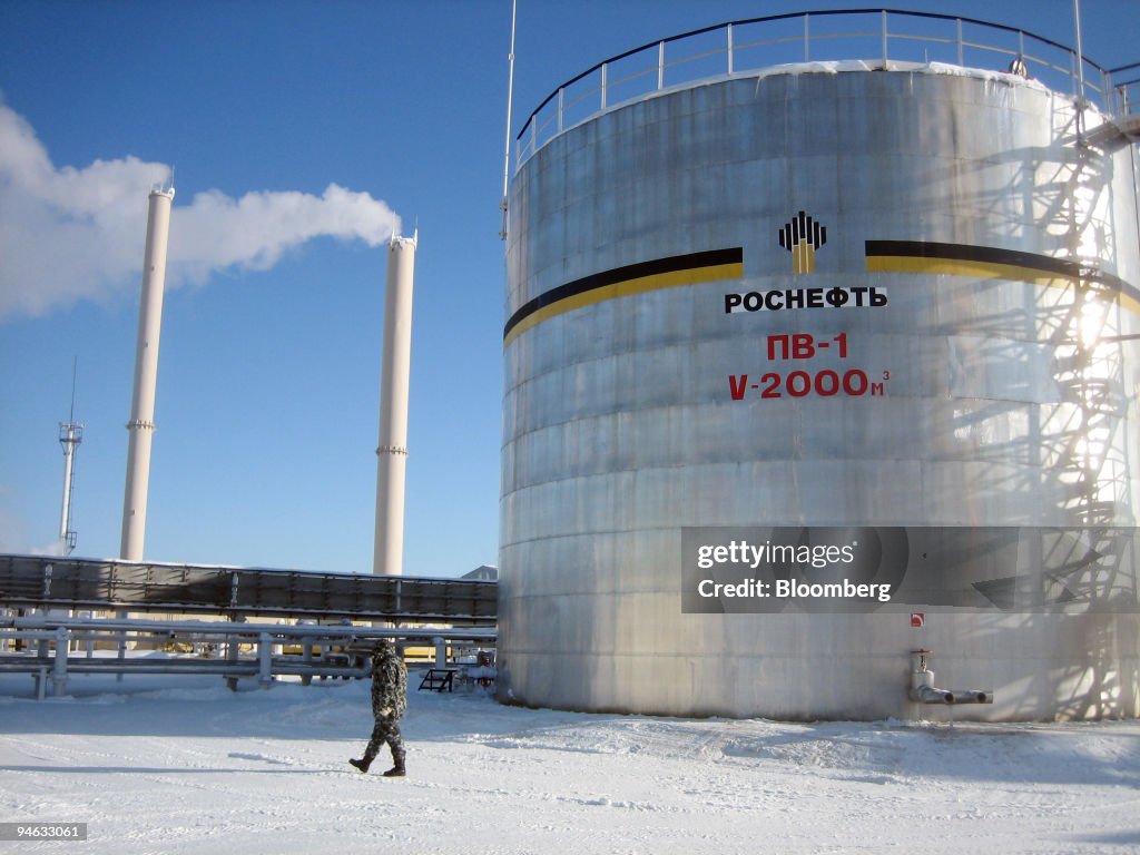 A guard passes an oil storage tank at OAO Rosneft's Priobsko