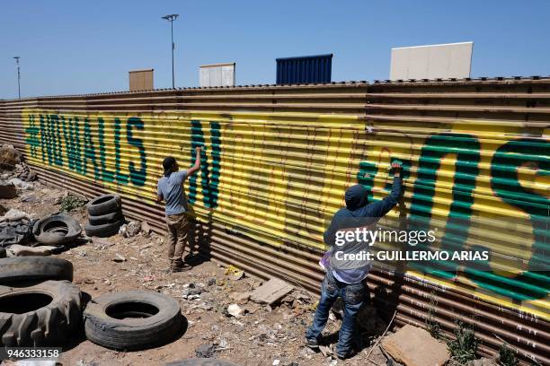 Activists paint the US-Mexico border wall, as part of the "Picnic prototype, Security through Friendship" activity at the border near US President...