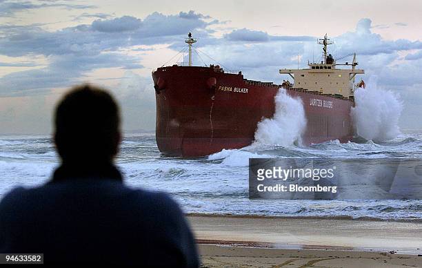 Spectator watches as waves crash against the coal freighter Pasha Bulker, which ran around at the entrance to Newcastle Port, north of Sydney,...