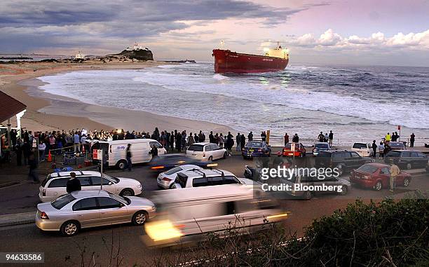 Spectators gather to watch as waves crash against the coal freighter Pasha Bulker, which ran around at the entrance to Newcastle Port, north of...