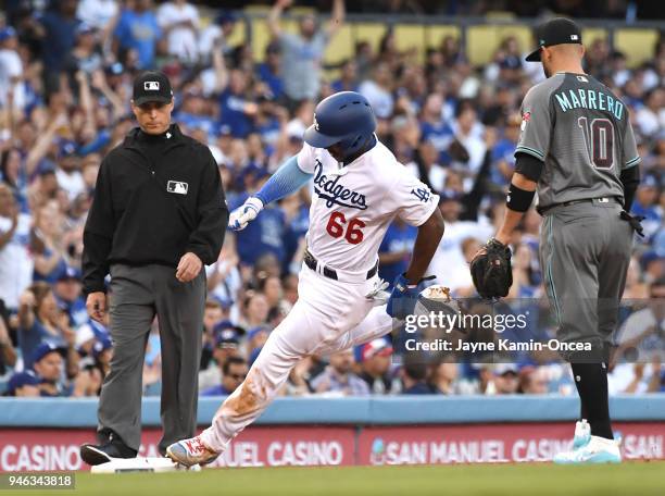 Umpire Dan Iassogna and Deven Marrero of the Arizona Diamondbacks watch as Yasiel Puig of the Los Angeles Dodgers tags third base as he heads home to...