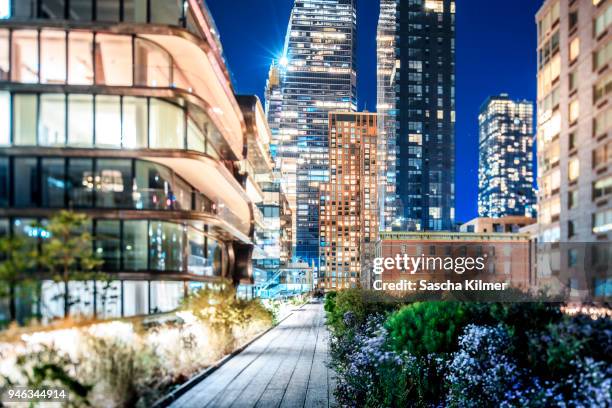 brightly lit buildings along the high line at night - chelsea hotel stock-fotos und bilder