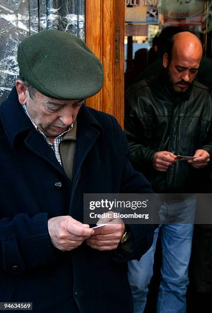 Customers look at their lottery tickets as they leave a kiosk in Bilbao, Spain, on Tuesday, Dec.18, 2007. The ''El Gordo'' Christmas lottery, has a...