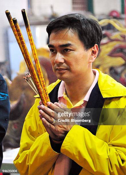 Abhisit Vejjajiva, the leader of Thailand's Democrat Party, makes an offering of incense sticks during a campaign visit to a temple in Chinatown, in...