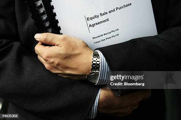 Man holds a copy of the equity sale and purchase agreement after a signing ceremony between Woodside Petroleum Ltd., Kansai Electric Power Co. And...