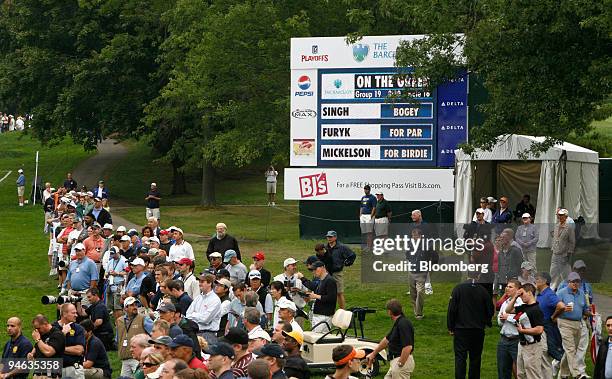 Spectators stand on the sidelines near an LED scoreboard displaying statistics supplied by SHOTLink during the Barclays Classic golf tournament at...