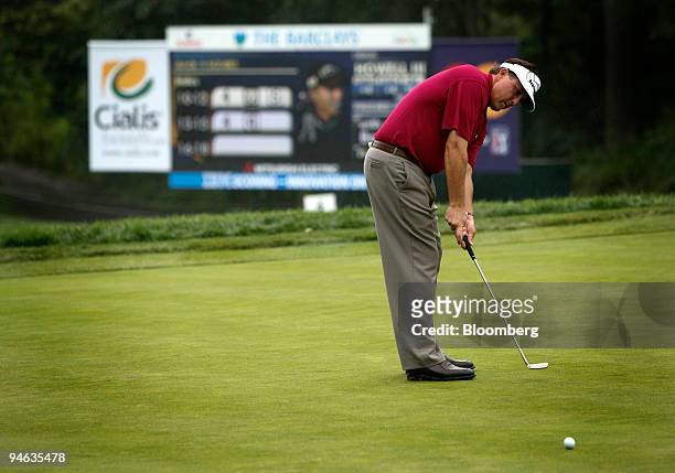 Golfer Phil Mickelson makes a putt in front of an LED scoreboard displaying statistics supplied by SHOTLink during the Barclays Classic golf...