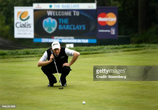 Golfer Jim Furyk lines up a putt in front of a LED scoreboard displaying statistics supplied by SHOTLink during the Barclays Classic golf tournament...