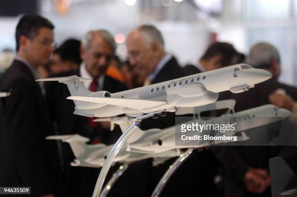 Visitors to the Latin America Aero & Defense trade fair stand near Embraer aircraft models at the company's stand in Rio de Janeiro, Brazil, on...