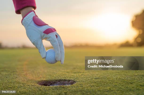 het verwijderen van de golfbal uit het gat bij zonsondergang - roze handschoen stockfoto's en -beelden