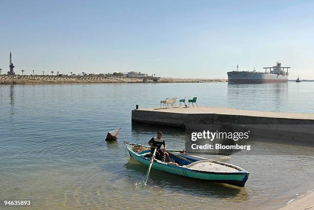 Fishing boat waits on shore as a northbound single hull oil tanker sails on the Suez Canal in Ismailia, Egypt on Tuesday, December 11, 2007. Egypt...