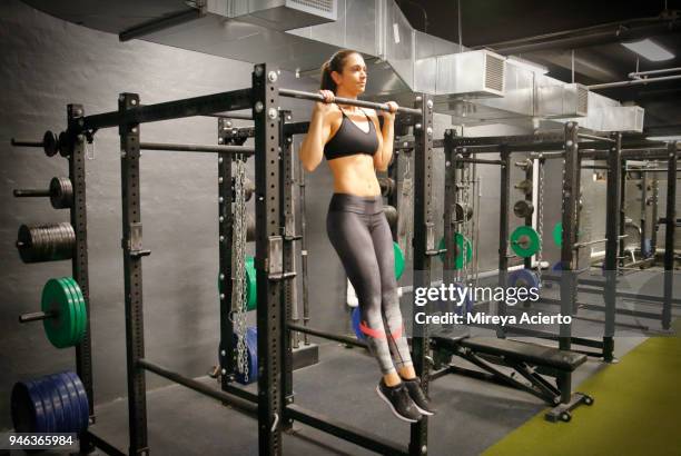 strong, caucasian woman doing pull ups in a fitness gym. - chin ups stockfoto's en -beelden
