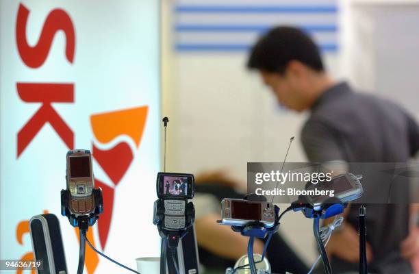 Mobile phone handsets are displayed in an electronics shop where an SK Telecom advertising board is displayed in Seoul, South Korea, on Saturday,...