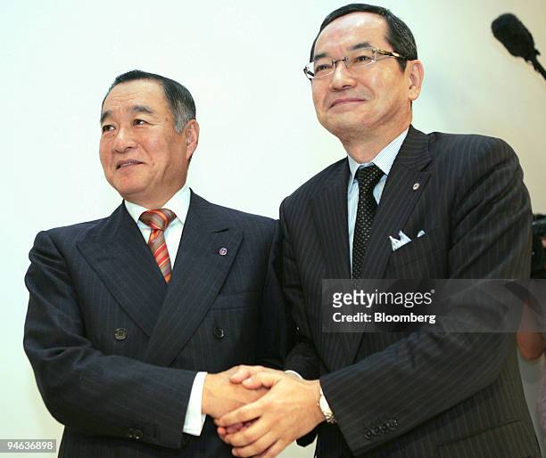 Nobukazu Muto, president of Isetan Co., left, and Kunio Ishizuka, president of Mitsukoshi Ltd., shake hands following a joint news conference in...