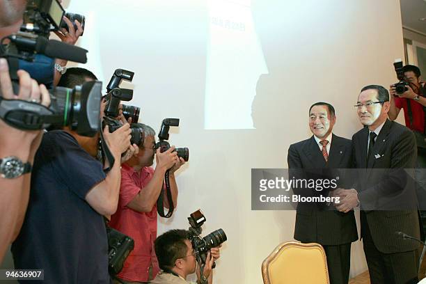 Nobukazu Muto, president of Isetan Co., left, and Kunio Ishizuka, president of Mitsukoshi Ltd., pose for photographers following a joint news...