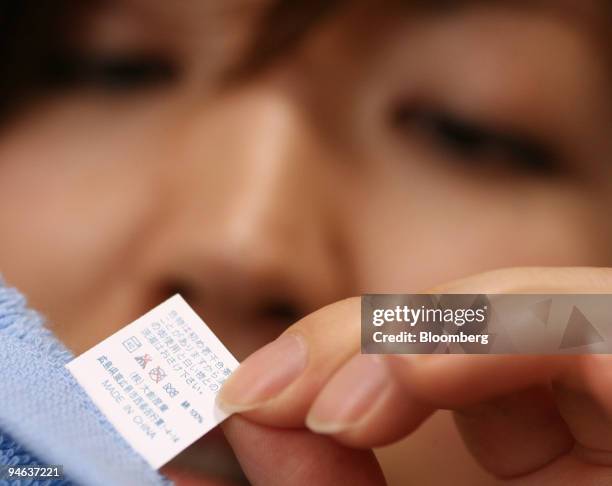 Woman looks into a label indicating " Made in China" on a towel in Tokyo, Japan, on Friday, June 8, 2007.