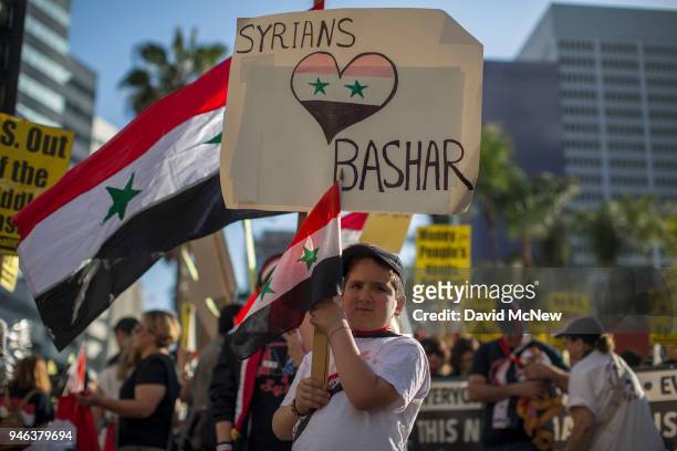 Boy carries a sign and flag as supporters of Syrian president Bashar al-Assad protest the U.S.-led coalition attack in Syria, on April 14, 2018 in...