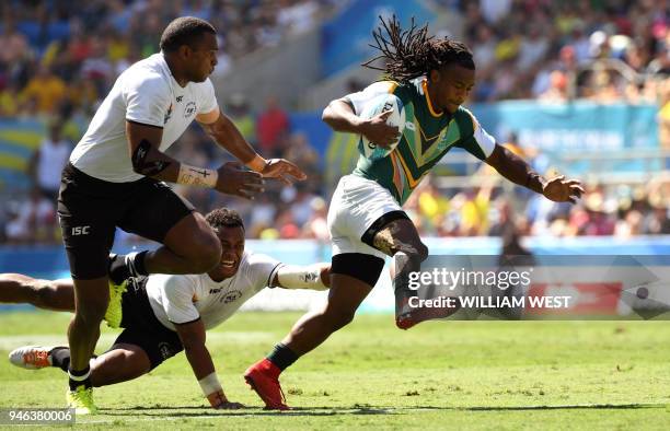 Justin Geduld of South Africa is tackled by Fiji's Amenoni Nasilasila and Ratu Vakurinabili in the men's rugby sevens semi-final match at the Robina...