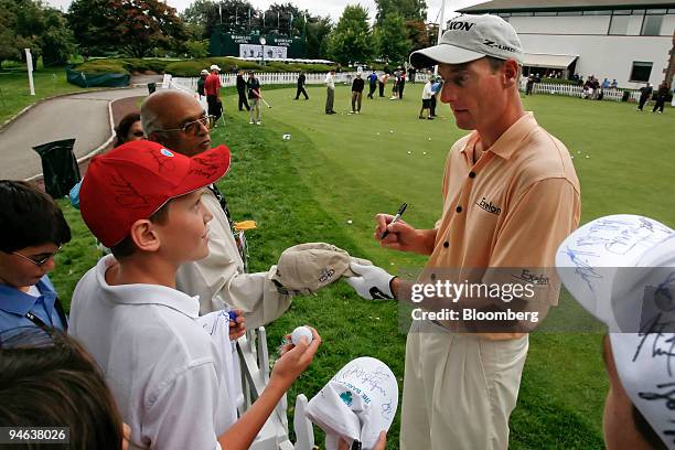 Professional golfer Jim Furyk, right, signs autographs for fans on a practice putting green a day ahead of the Barclays Classic at Westchester...